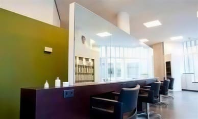 Kappersstoelen langs een spiegelwand, met een mosgroene wand ernaast.