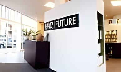 De entree van de salon met de naam Hair Future in zwarte letters op de witte muur.